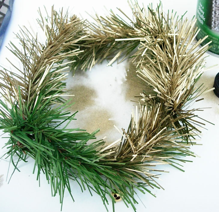spray painting a green wreath ornament gold