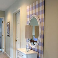 Create more intrest on a wall by layering wall art or mirrors on canvas covered with fabric