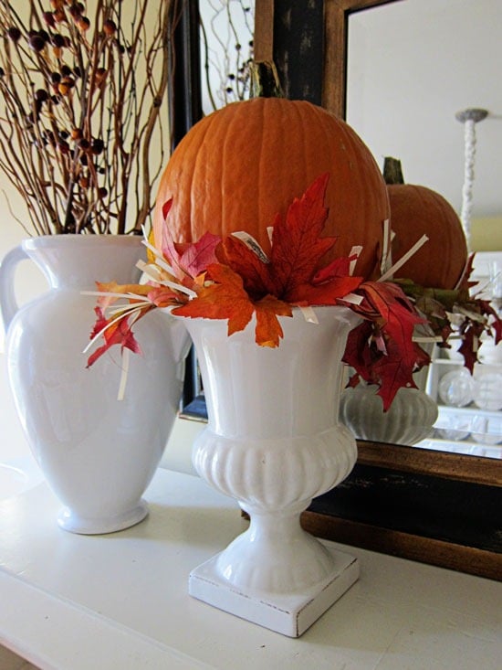 A white urn make into a fall pumpkin vase. 