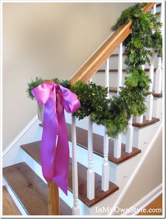 Fuchsia satin ribbon and evergreen garland on a foyer staircase railing