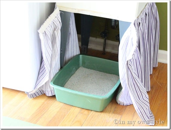 Skirted fabric attached around a laundry room tub sink makes for a good place to hide a litter box that allows the cat to still easily use it.