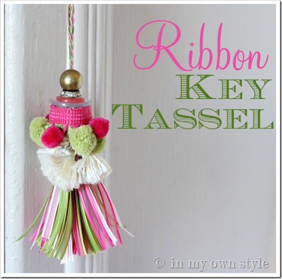 Key tassel made using pink and green ribbons hanging from a lock on a door.