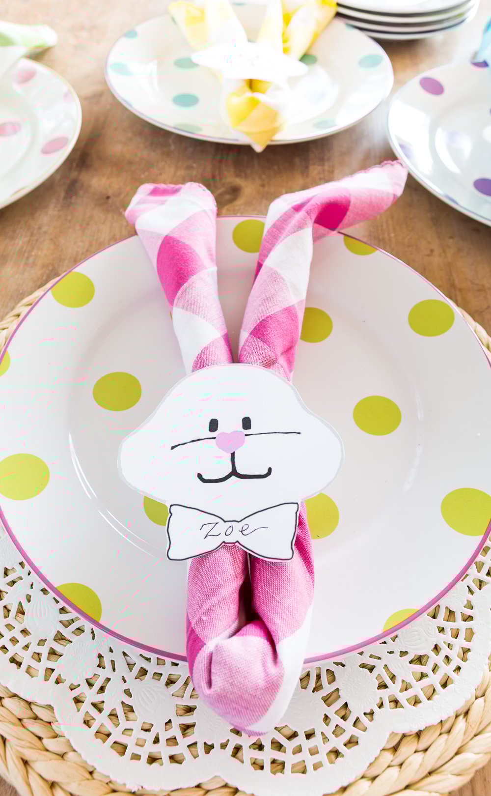 Pastel Pink Buffalo Check Napkin folded to make an Easter bunny napkin holder on a plate.