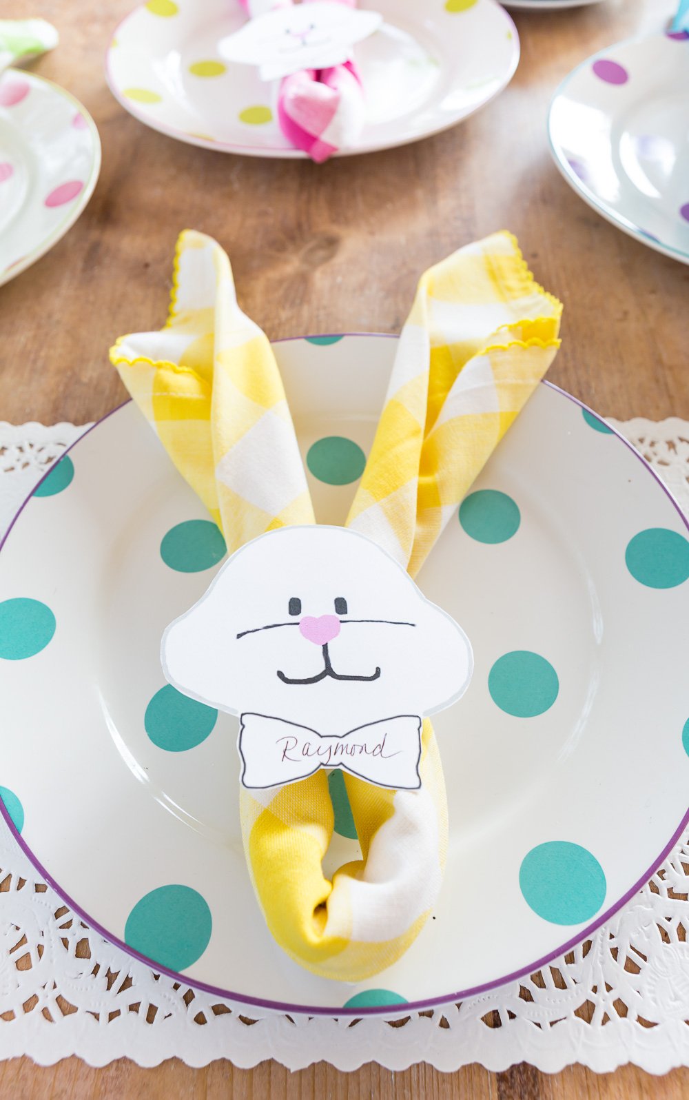 Yellow and white Bunny place card on turquoise polka dot dinner plate.
