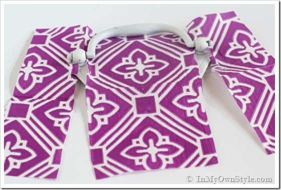Furniture drawer pulls getting covered in a purple and white paper napkin.