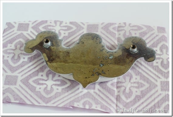 How to transform a drawer pull with a napkin. Pull is laying face down on back side of napkin.