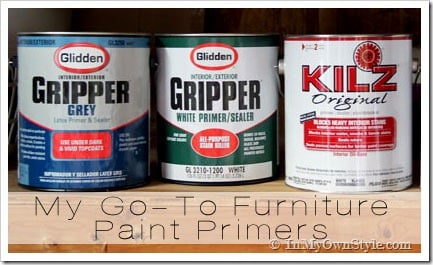the-Best-Paint-Primers on a garage shelf. Glidden Gripper in white and grey and Kilz Original formula.