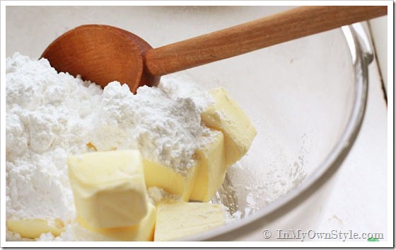 Cookies-to-make using real butter. Mixing butter and flour together in bowl.