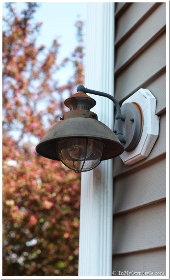 Rusty outdoor light fixture on side of a house.