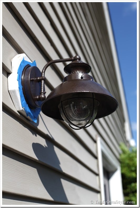 Outdoor light fixture with painter's tape around it getting a coat of fresh paint.