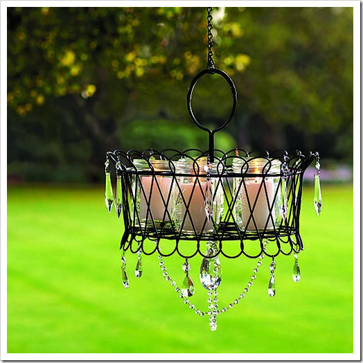 Wire basket hung from tree with mason jar candle holders inside.