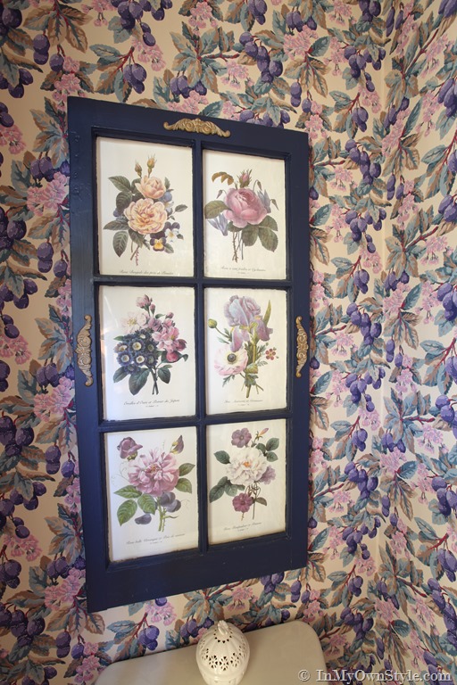 An old wood glass fronted kitchen cabinet found in curbside trash becomes wall art in a home. 
