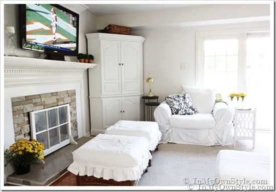 Two white slipcovered ottomans in a white decorated family room.