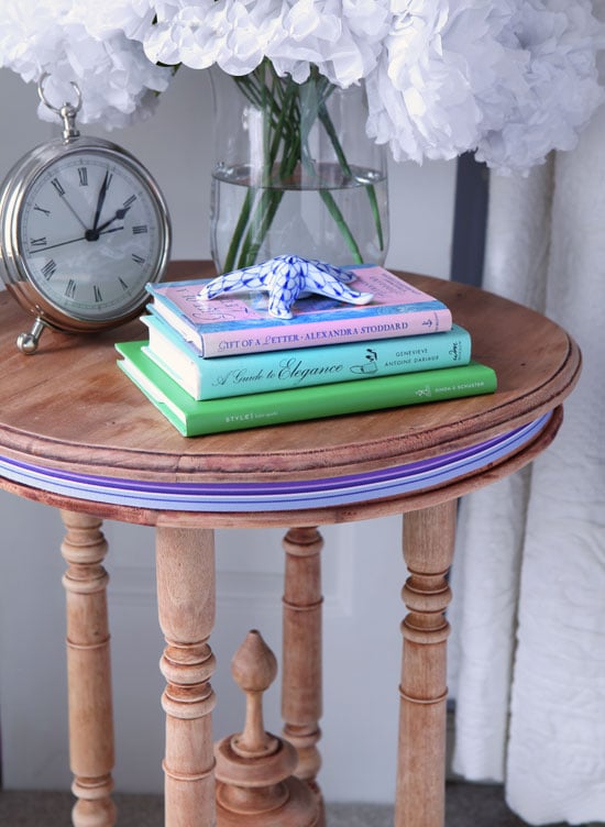 a stripped side table with striped ribbon around the top as a decorative accent.