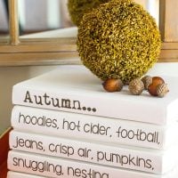 A stack of white books on a table top with fall sayings on the bindings. Free printable to download to use