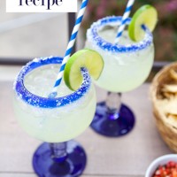 This is the Margarita recipe you have been searching for. It is the best! 2 margarita glasses on a table with limes and green and white striped straws.
