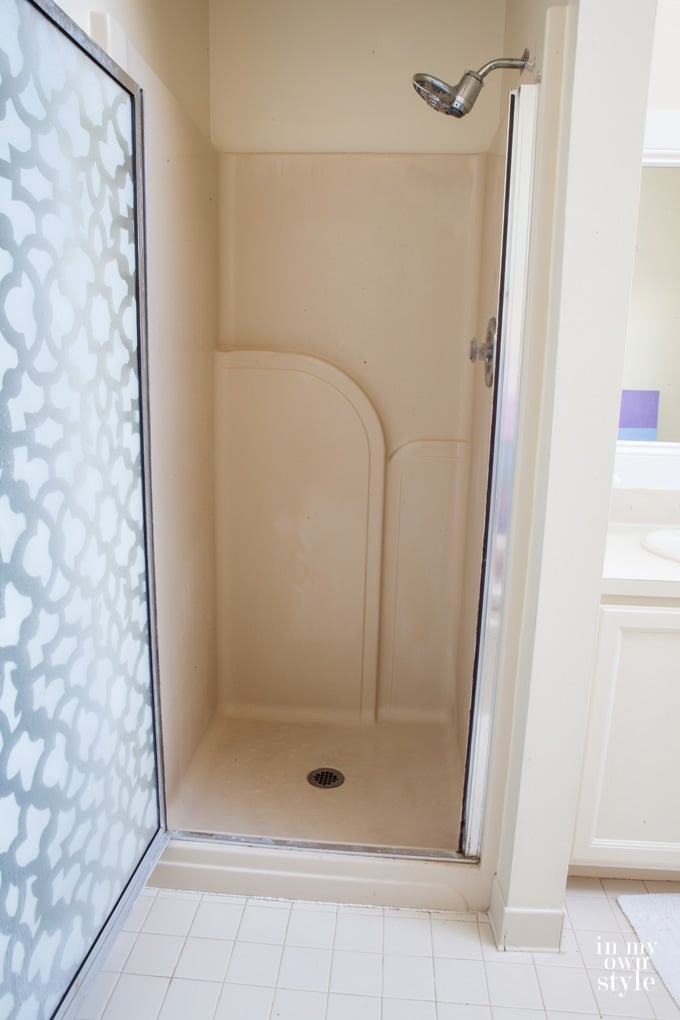 Stall-shower-makeover-before image. Door has a white pattern on it and shower is molded plastic.