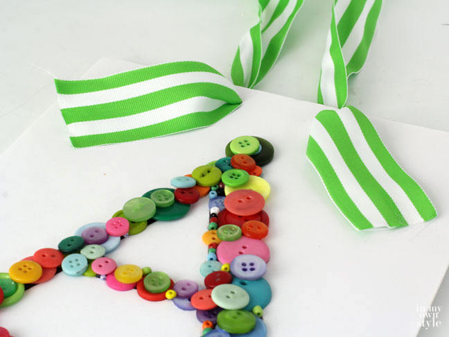 adding ribbon to letter button letter art so it can be hung on a wall.