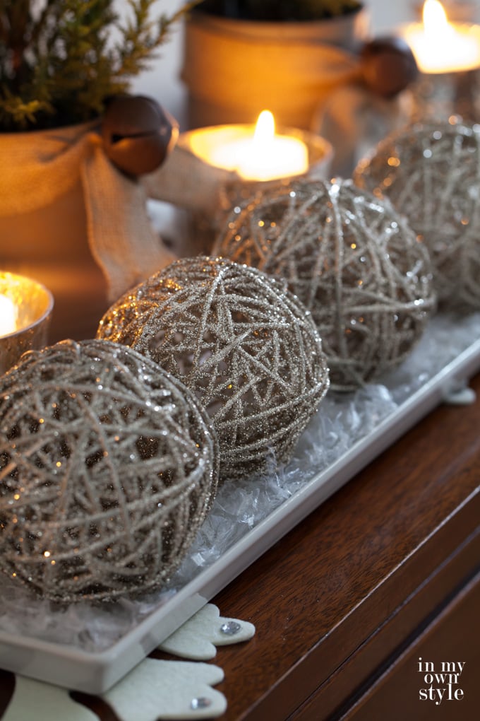 3 glittered spheres and candles on Christmas decorated console table