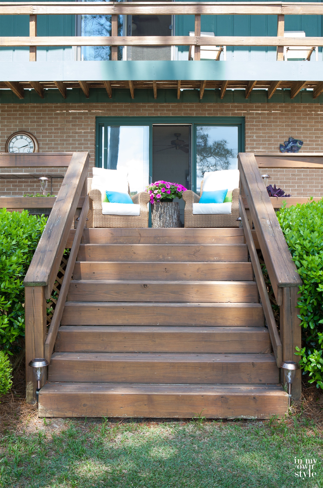 Deck staircase with two rattan chairs at the top and a tree trunk table between them.