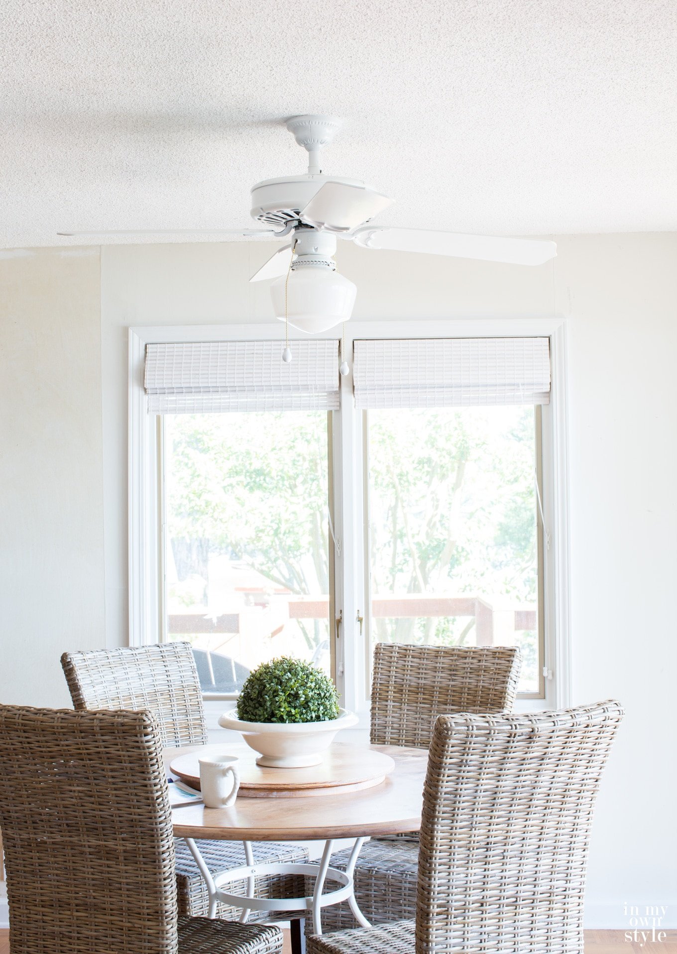 Photo of newly painted ceiling fan over a round dining table and wicker chairs.