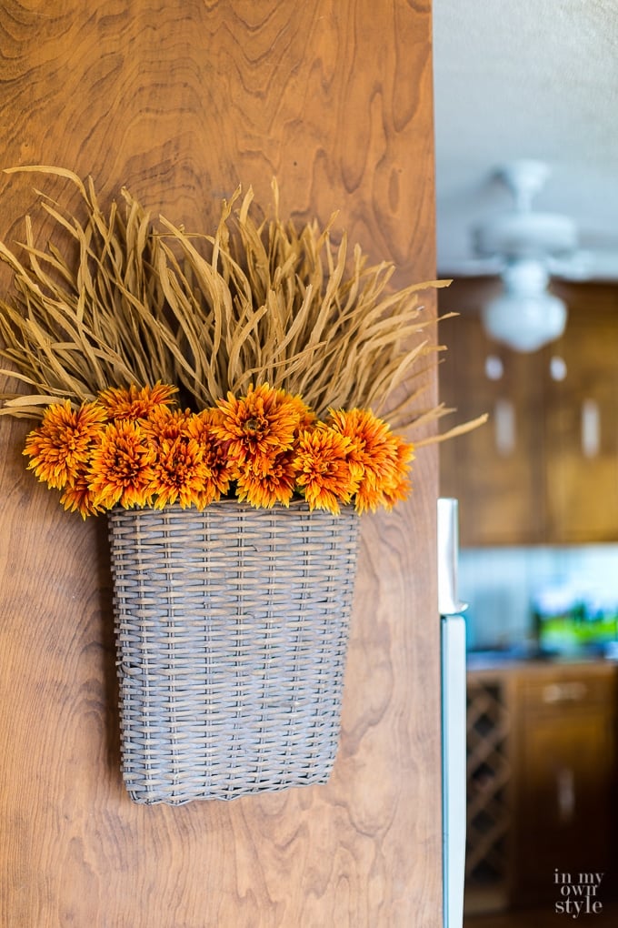a hanging basket filled with dried fall flowers used in place of a vase.