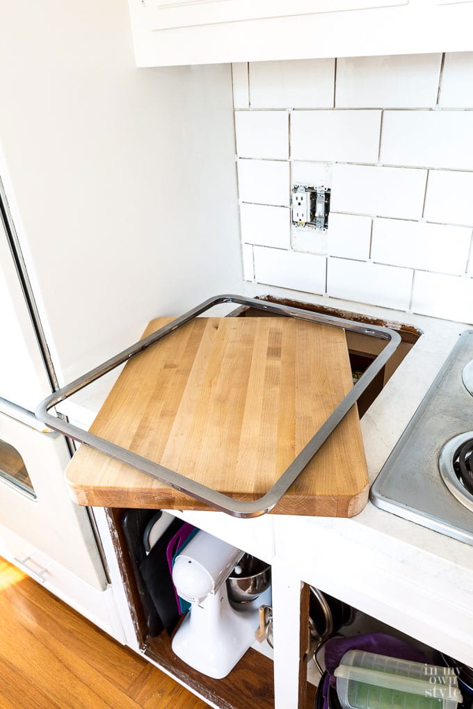 Butcher block cutting board in set in kitchen counter with stainless steel friend.