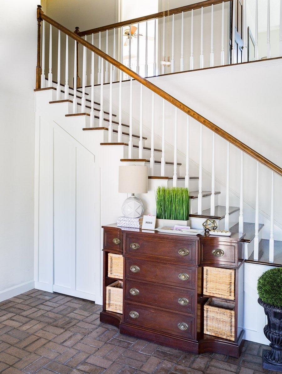 Closet with hidden door under staircase and sideboard with wicker baskets 