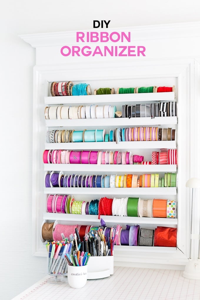 Ribbon organizer on a wall with rows of rolls of colorful ribbons.
