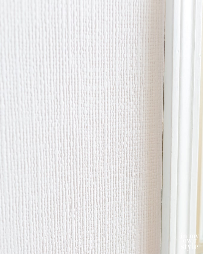 close up photo showing white textured wallpaper on a wall in a kitchen. 