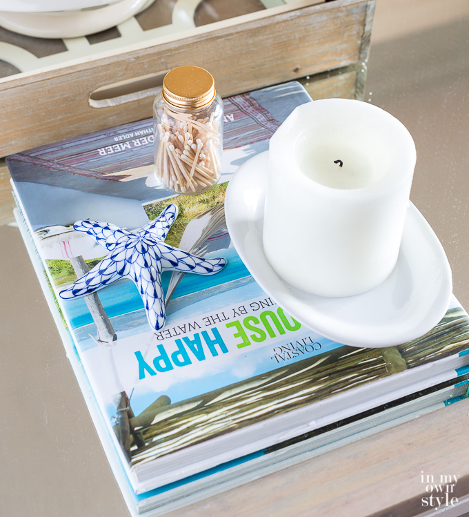 summer coffee table decorating ideas - a book with a candle, ceramic starfish and glass bottle of matches