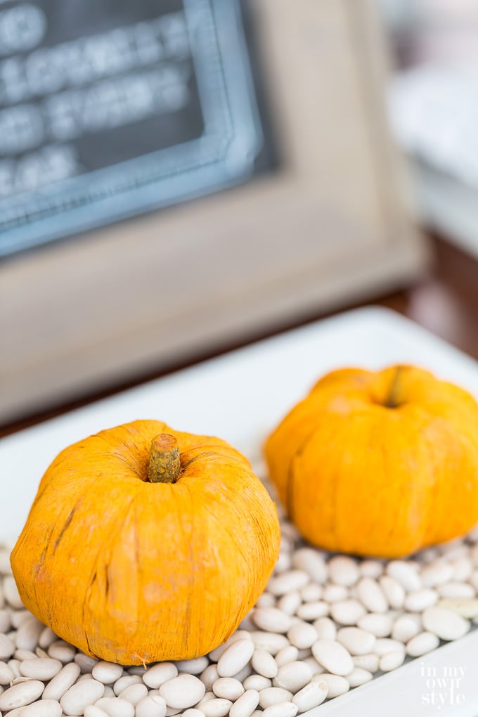 Paper pumpkins on a bed of white beans on a tray