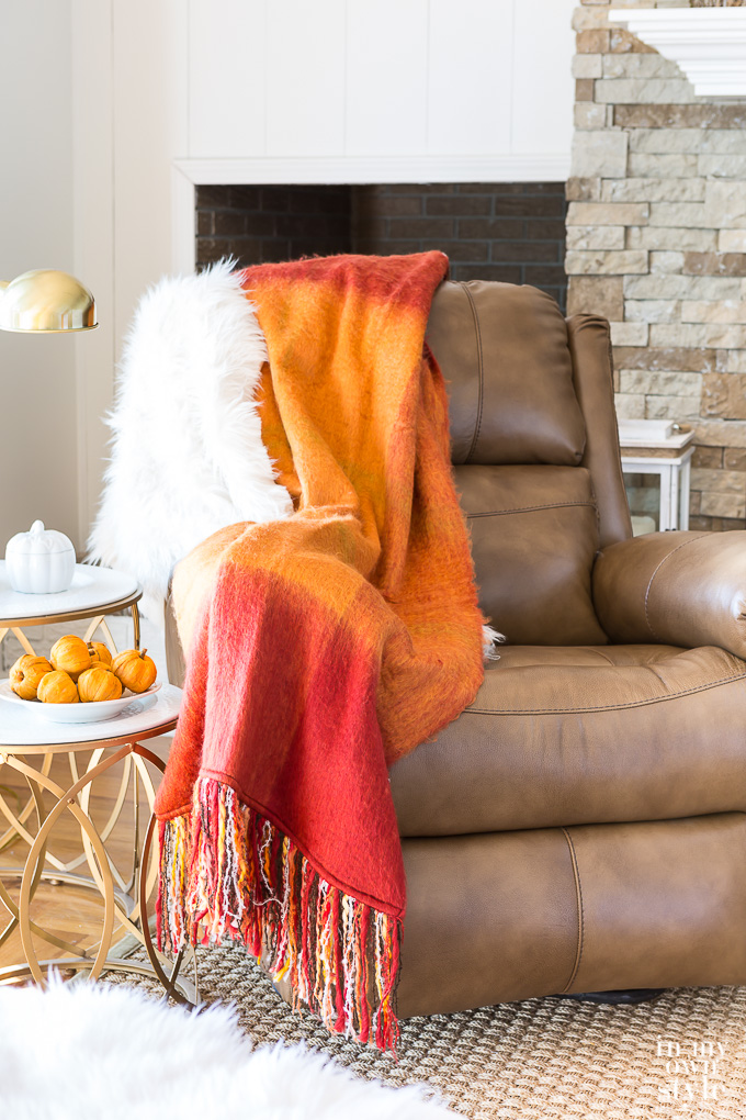 Leather recliner in living room with fall throw blanket and fur over the arm. 