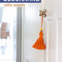 Orange raffia tassel hanging on a white door for fall decorating.