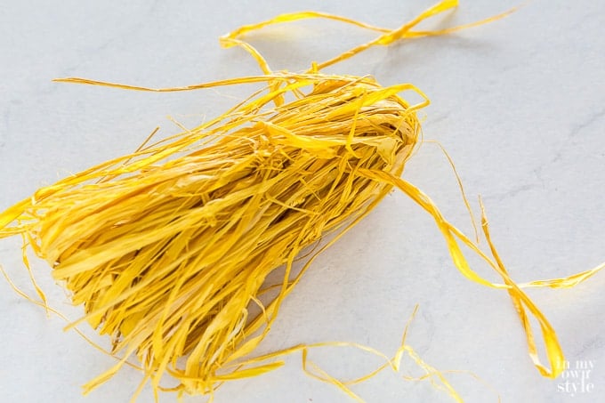 Yellow raffia being made into a fall decorating tassel