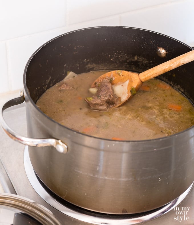 Beef stew being made in a pot on the stove.