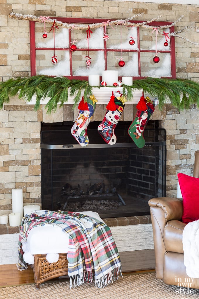 Christmas mantel decorating idea that repurposes an old window sash and tree branch to create holiday spirit above the fireplace.