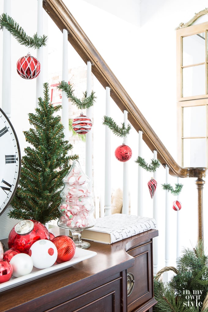 Christmas staircase decorated using garland ties and a collection of red ornaments.
