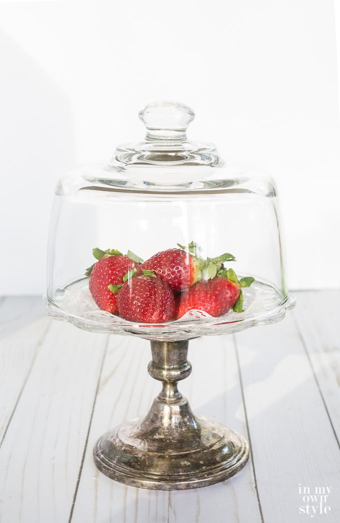 glass dome over a pedestal plate of strawberries