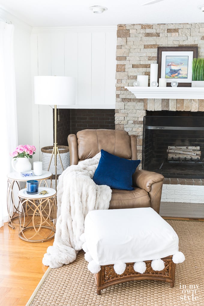 Living room with stone fireplace, brown recliner and metal wire side tables. 