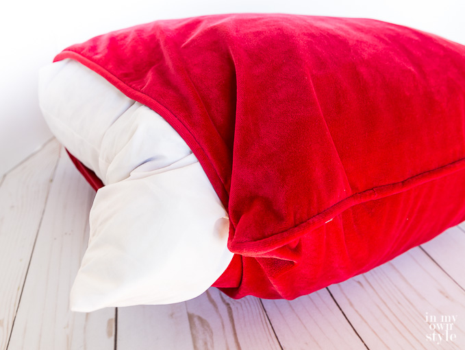 red velvet pillow cover being placed on a pillow insert.