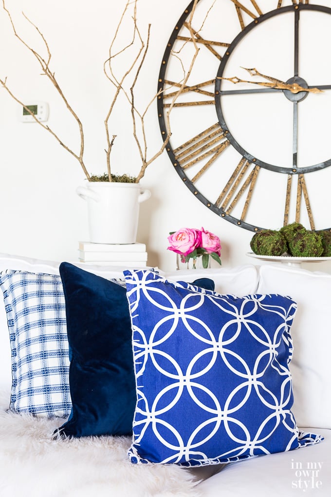 3 navy blue and white pillows on a sofa made using napkins that work well for spring home decor or any season.