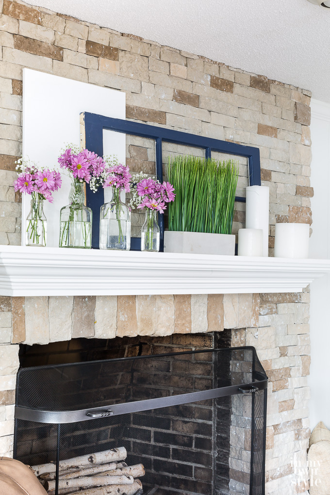 Pin and green spring mantel decor using glass bottles and repurposed items.