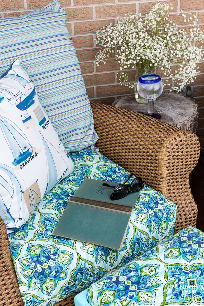 outdoor chair cushions, pillows and open book on rattan rocker.