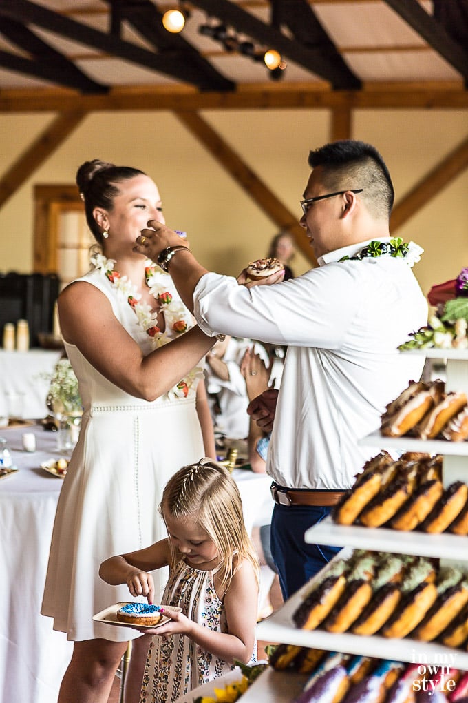 Eating donuts at a wedding with a DIY tiered donut stand for a wedding or party in the background.