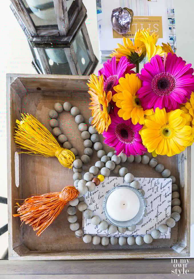 Wood tray decorated for fall with flowers and wood bead garland