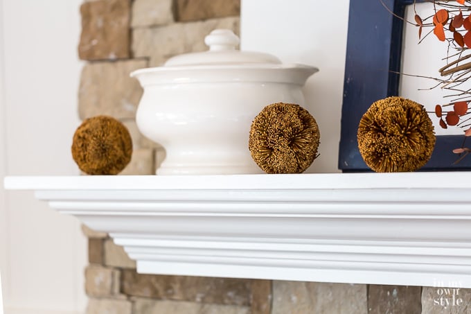 3 rustic balls on a white mantel decorated for fall