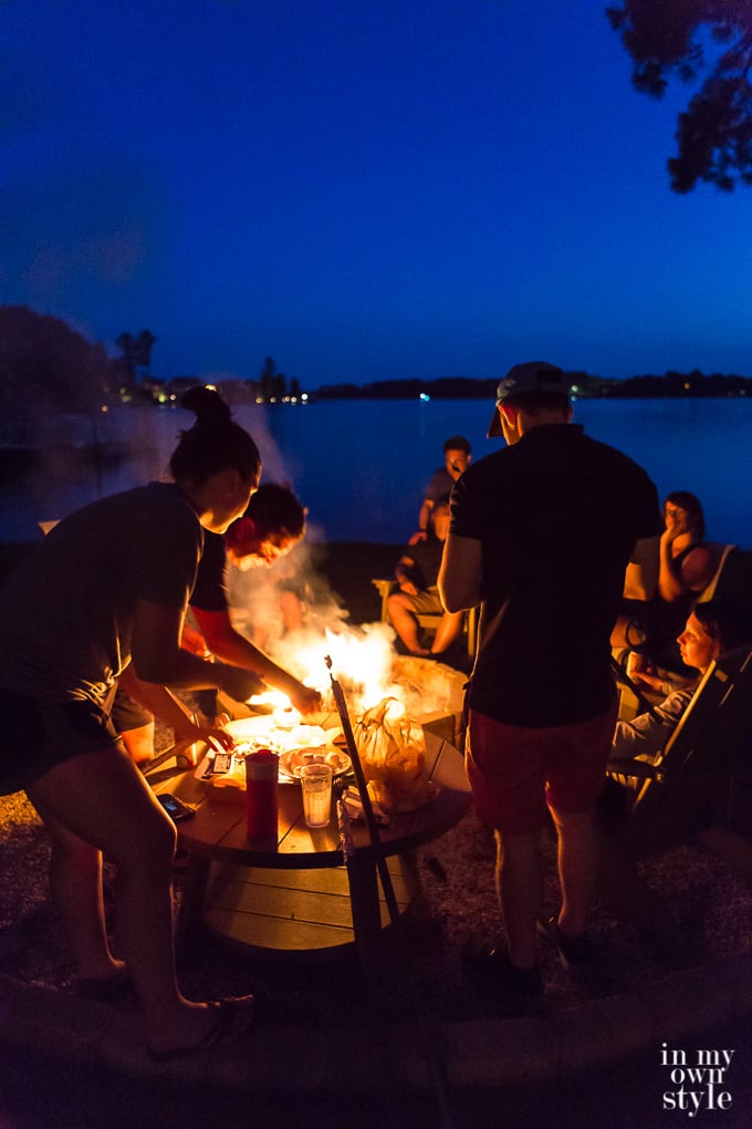 People Standing around an outdoor fire roasting marshmallows