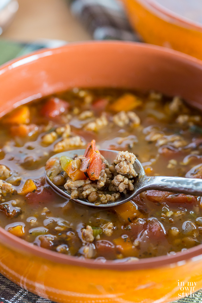 sausage and lentil soup being spooned out of a soup bowl.