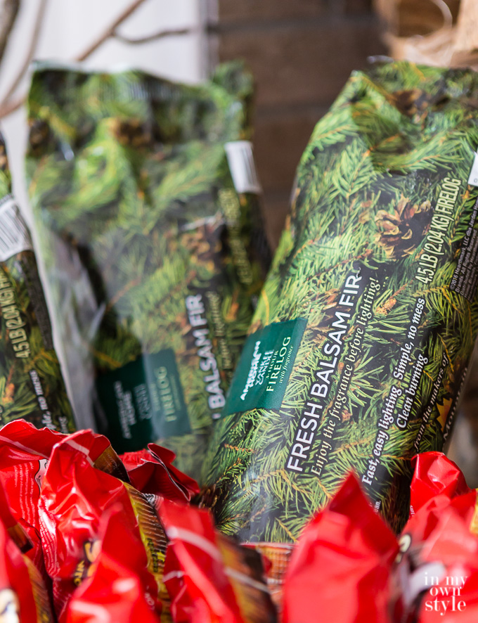 American Home™ by Yankee Candle® Balsam Fir Firelogs stacked in a basket by a fireplace.